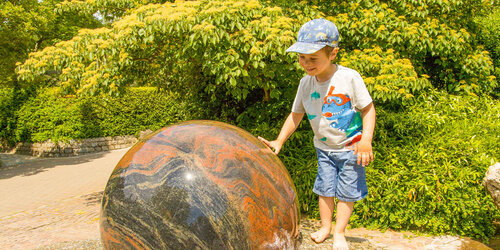 Kind mit Schwimmender Granitkugel