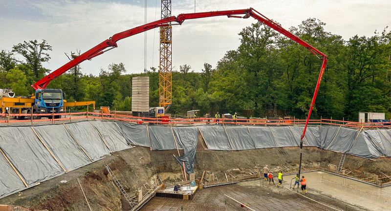 Foto von Betonpumpe, die Bodenplatte gießt.
